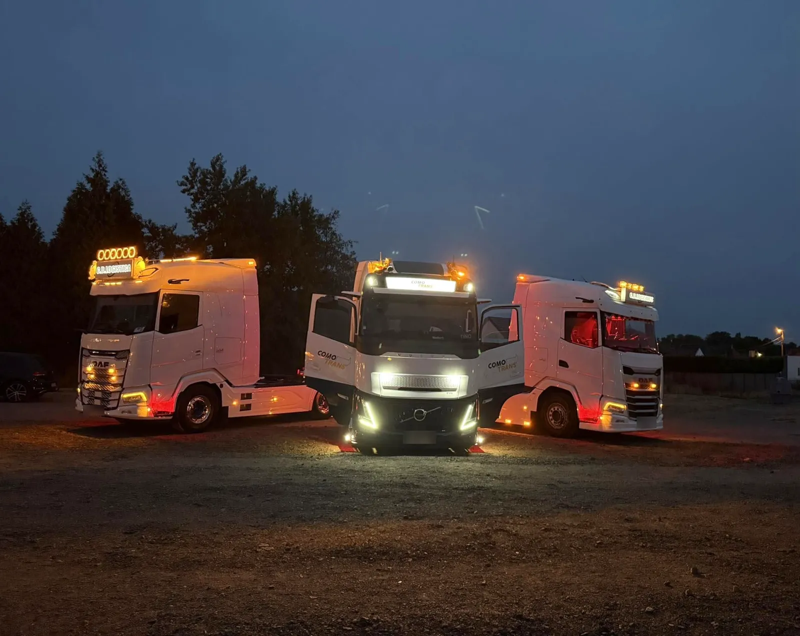 Trois camions équipés, éclairés au crépuscule